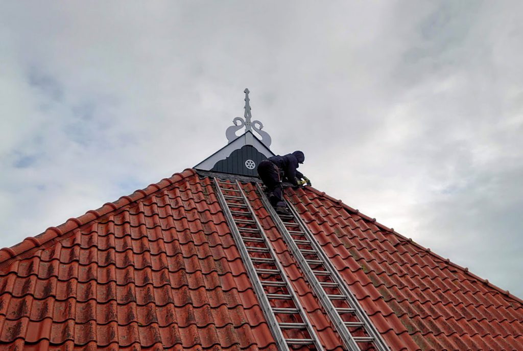 Restauratie aan het uilebord op dak